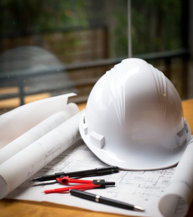 construction concept image helmet rolled blueprints on wooden bo